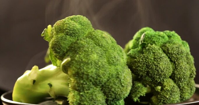 Green fresh broccoli with steam rotating at black background