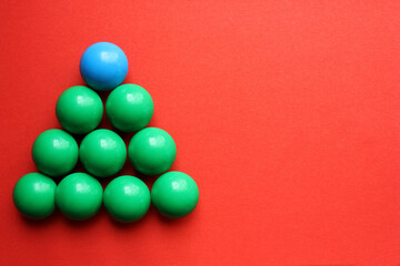 Green Christmas tree from a children mosaic on a red background. New Year and Christmas decorations. Close. The object is on the left. The concept of holidays. Flatley. View from above. Copy space.