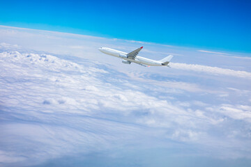 Fototapeta na wymiar Commercial airplane flying above blue sky and white clouds.
