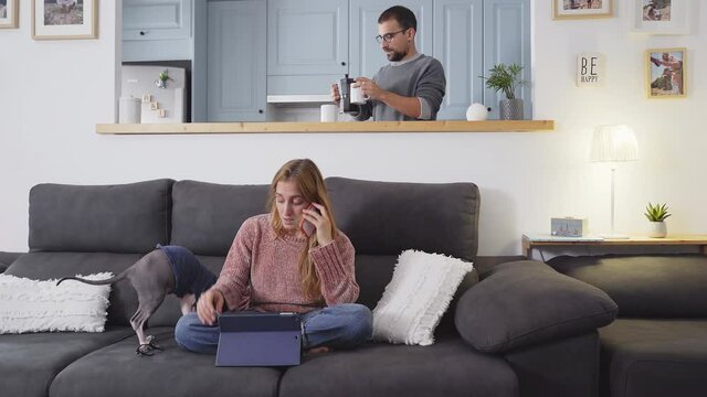Woman working at home with laptop. Your partner serves you a coffee. Domestic scene.