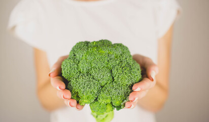 girl holding green fresh broccoli in her hands on the white background