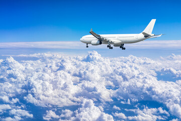 Naklejka na ściany i meble Commercial airplane flying above blue sky and white clouds.