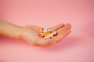 some medicine of various shape and colors on the man's hand