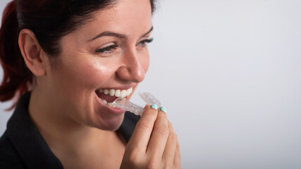 Business woman puts on transparent retainers to straighten teeth