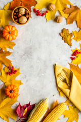 Thanksgiving dinner background with pumpkins leaves and cutlery, top view