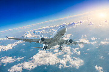 Commercial airplane flying above blue sky and white clouds. - obrazy, fototapety, plakaty