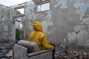 a man in a yellow raincoat sits in an armchair in the middle of an empty abandoned room in a...