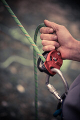 Man's hands operating a rock climbing belaying device