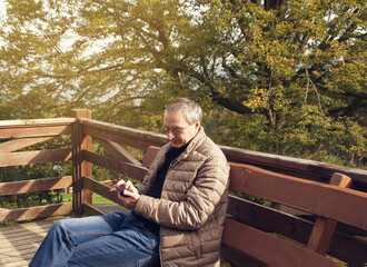 Fototapeta premium man holding a phone in the autumn forest 