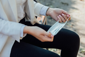 Obraz premium A beautiful businesswoman puts a surgical mask on her face. Prevention of coronavirus. 