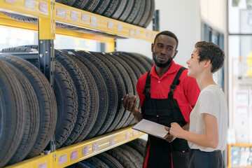An auto mechanic talking to female customer in tires shop, car auto service, garage