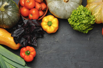 Assortment of vegetables including pumpkin, tomatoes and peppers on black background