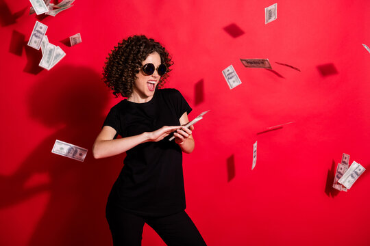 Photo portrait of woman throwing money in air isolated on vivid red colored background
