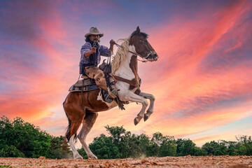 Silhouette and blur of action cowboy holding a gun on horseback. - obrazy, fototapety, plakaty
