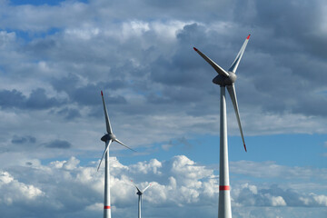 Wind turbines rising up into the sky with many clouds - Stockphoto