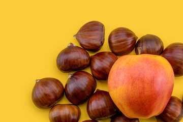 chestnuts and red royal gala apple isolated on yellow background in top view, copy space
