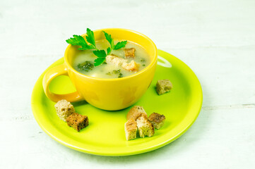 A cup of vegetable soup with crackers on a green plate