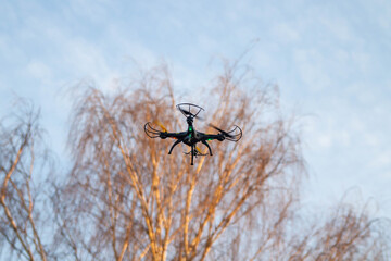 A quadrocopter drone flies high in the sky.