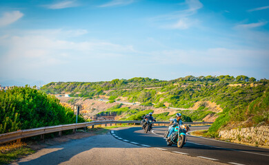 Fototapeta premium Group of Motorcycles on a winding road by the sea in Sardinia