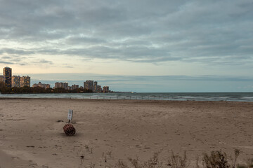 Epic shot of empty beach with highrise apartment buildings in distance with lights and cloudy sky