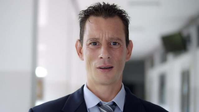 A business man wearing a suit and tie is puzzled, confused, and unable to decide.