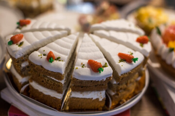 Carrot cake, decorated with cream-colored carrots on a stand for cakes.