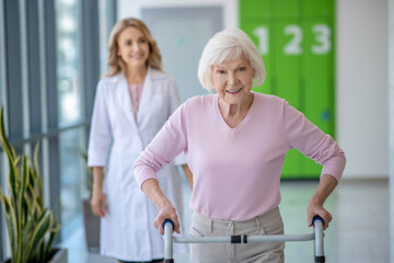 Obraz premium Senior woman with rolling-walker having rehabilitation procedures in clinic