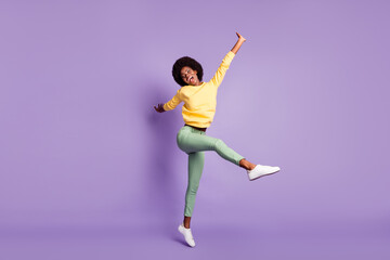 Fototapeta na wymiar Full length photo of excited afro american girl jump wear yellow pullover green trousers isolated on violet color background