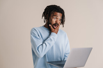 Shocked african american guy holding and looking at laptop