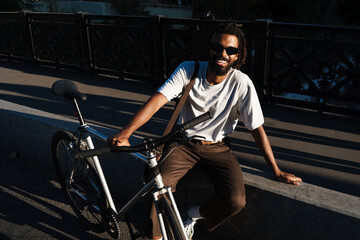 Fototapeta na wymiar Happy african american guy smiling while posing with bicycle
