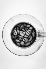 Black and white vertical image of coffee beans in vintage coffee pot in white background.