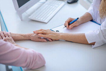 Doctor putting he rhand on patients hand showing concern
