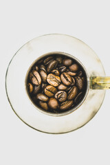 Close up macro of golden color coffee beans in silver container isolated in white background.