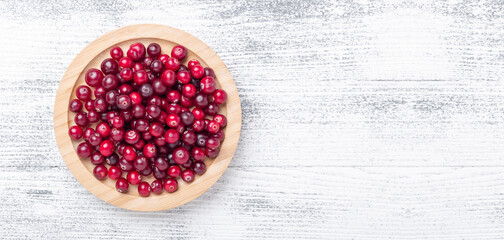 Horizontal banner with raw fresh cranberries in wooden bowl on light wood background. Top view. Copy space