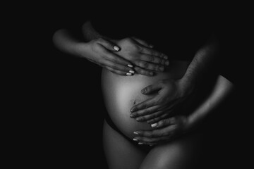Male and female hands hug a pregnant woman. Black and white shooting
