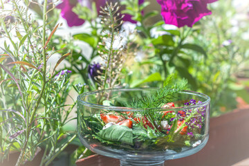 Summer vegetables salad with fresh strawberries, basil, mozzarella and edible flowers in glass salad-bowls in garden at sunny day. Healthy eating. Organic and vegetarian food