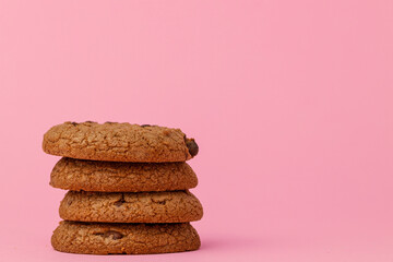 Stacked chocolate chip cookies against pink background