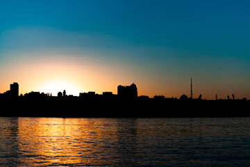 sunset over the city, the sun sets over the horizon, clear sky, in the foreground of the river, use as a background or text