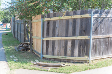 Aged wooden fence near new lumber boards installation of suburban residential house in Texas, USA