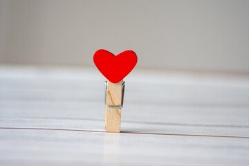 Clothes pin with a red heart as a concept of loneliness in the 21st century. Looking for love or...