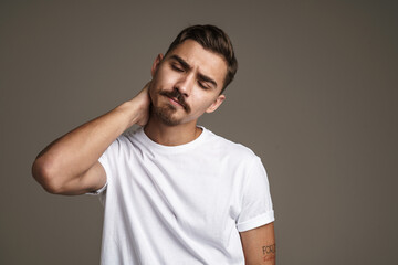 Obraz premium Image of tired handsome guy rubbing his neck while posing on camera