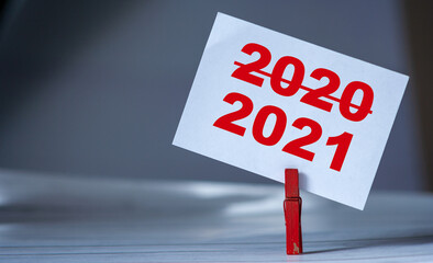 Reminder sticky note with clothes pin on table. Sticky note with crossed inscription 2020 and...