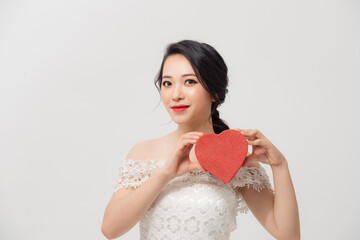 Portrait of young beautiful Asian girl holding love gift box over white background.