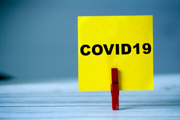 Reminder sticky note with clothes pin on table. Sticky note with word COVID19. Coronavirus pandemic...