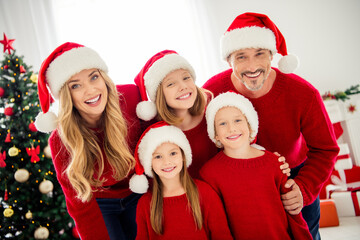 Portrait photo of family wearing warm red jumpers and headwear preparing home for christmas smiling laughing on xmas tree and decorations background