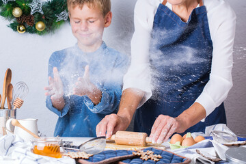 Grandmother with grandson cooking, kneading dough, baking in the kitchen