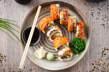 Sushi maki rolls with salmon, eel, avocado, cucumber on a plate with chopsticks, soy sauce, wasabi...