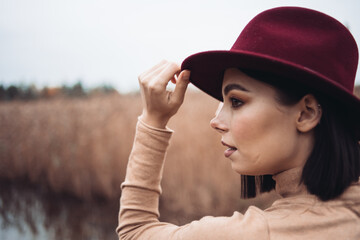 Outdoor fashion photo of young beautiful lady in autumn landscape with dry flowers. Autumn/Winter....