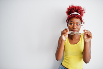 African american woman in yellow singlet and eyglasses against white wall.