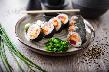 Sushi maki rolls with tuna, flying fish caviar, crab, avocado on a plate with chopsticks, soy sauce, wasabi and ginger. Japanese traditional food closeup served for lunch in modern gourmet restaurant